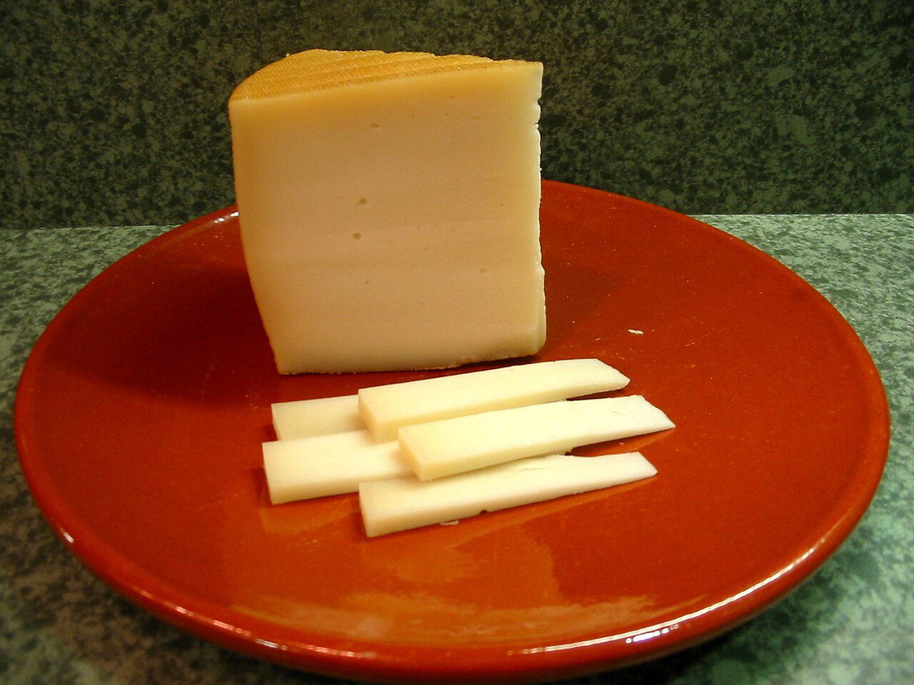 Cuña de queso Idiazabal cortada en lonchas sobre un plato de barro