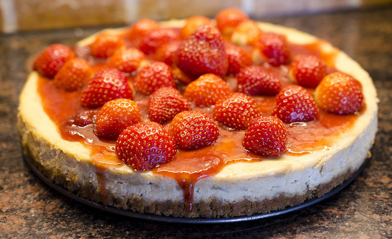 Whole strawberry cheesecake topped with fresh strawberries